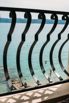 Two kids playing in the sea captured from behind a balcony grid