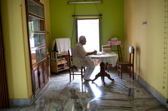 Elderly man sitting in sofa writing at home.