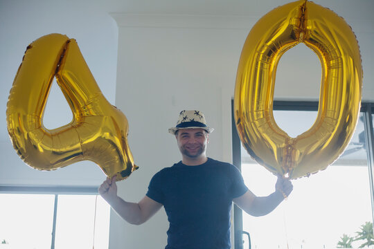 Man holding 4 and 0 numeral balloons