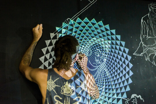 Artist drawing mandala on wall with projector