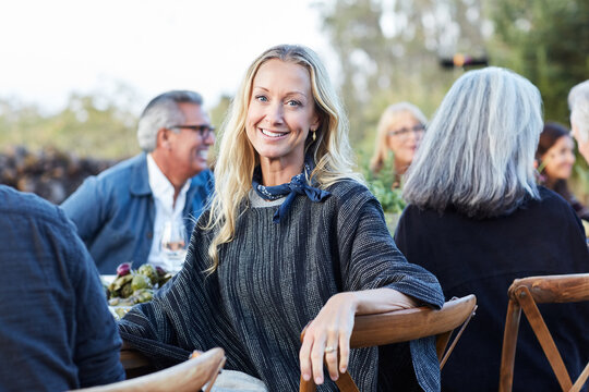 Portrait of woman with group of friends enjoying a Farm To Table Dinner Party in backyard