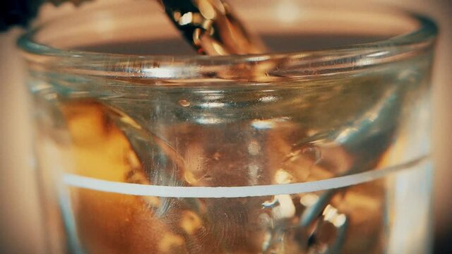 Pouring a shot of tequila alcohol in a shot glass close up macro slow motion