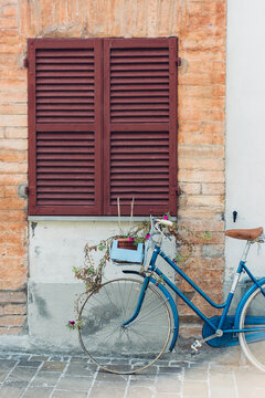 A bike with real flowers on the front leaning against a wall in Italy