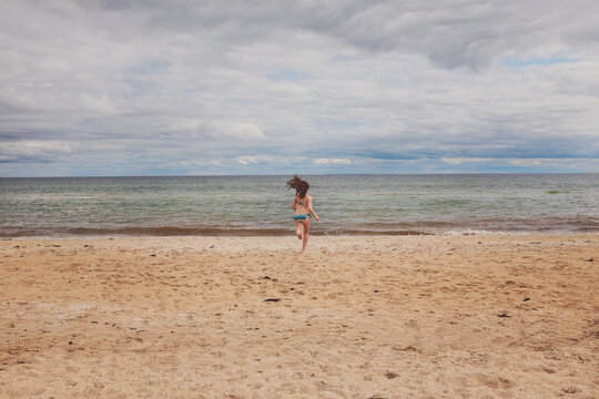 Girl running into water on scenic beach