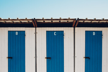 A row of blue doors; B, C and D against a blue sky