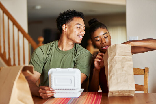 african american couple sitting at table looking at food delivery