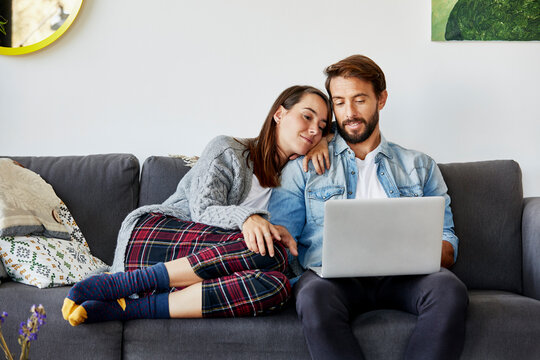 Young Woman With Man Using Laptop On Sofa