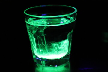 A Glass with a Glowing Green and Yellow Liquid Swirling Around Inside