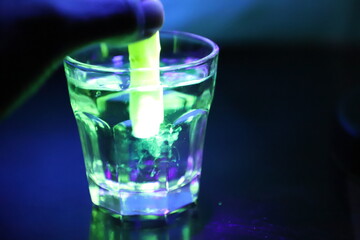 A Glass with a Glowing Green and Yellow Liquid Swirling Around Inside