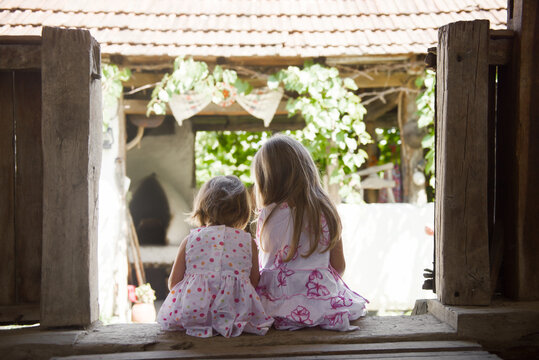 Rear view of two little girls sitting on house porch