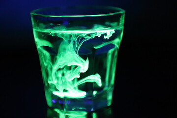 A Glass with a Glowing Green and Yellow Liquid Swirling Around Inside