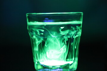 A Glass with a Glowing Green and Yellow Liquid Swirling Around Inside