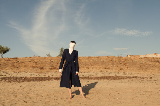 woman wearing coat and covering her face with r turtleneck sweater at beach
