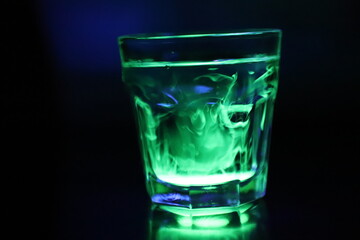 A Glass with a Glowing Green and Yellow Liquid Swirling Around Inside