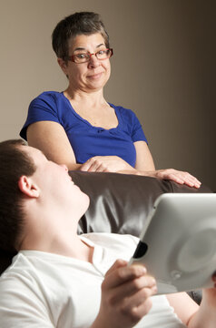 Woman looking at teenager using a tablet computer