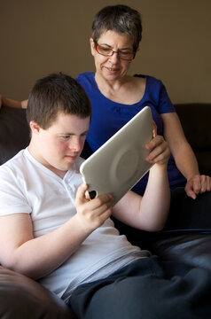Mother watching teenager using a tablet to play video game