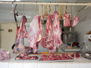 Raw cut pork pieces hanging in butchery