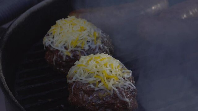Cheese melting on burgers over a hot grill 