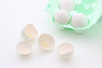 Broken white eggshell and tray with eggs