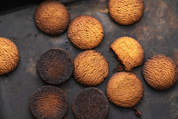 Burnt cookies. Burnt oatmeal cookies lie on a black baking sheet.