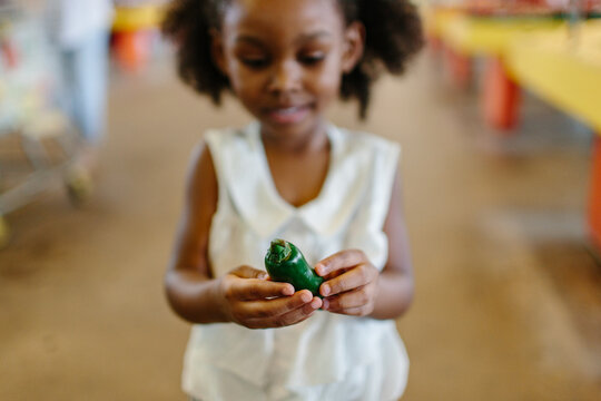 A little girl holding a green pepper
