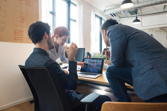 Office - Three Young People Looking at Financial Statistics on Laptop