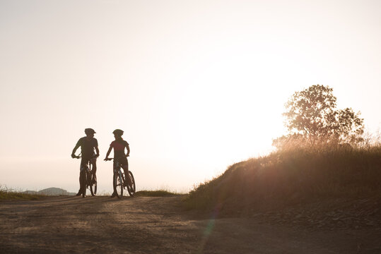 Couple of cyclists are looking to each other during sunset
