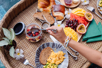 Woman having tropical healthy breakfast at villa on floating table   © Анастасия Каргаполов