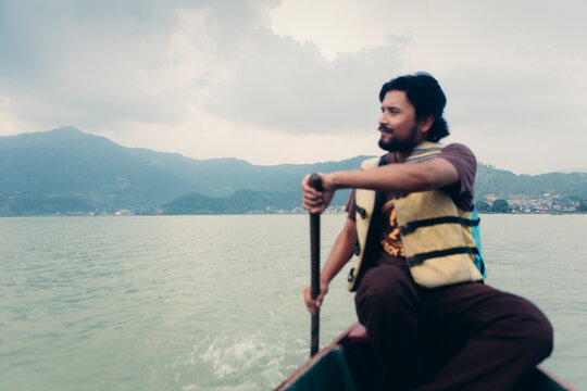 Young man rowing a boat.