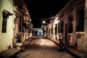 Fototapeta na wymiar View to typical street with one story buildings at night in light of lanterns, Santa Cruz de Mompox, Colombia, World Heritage