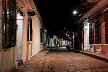 Naklejka na ściany i meble View to typical street with one story buildings at night in light of lanterns, Santa Cruz de Mompox, Colombia, World Heritage