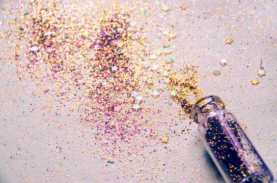 Shiny glitter spilled on the table from a tiny glass bottle