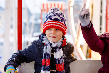 Two little kids, boy and girl having fun on ferris wheel on traditional German Christmas market...