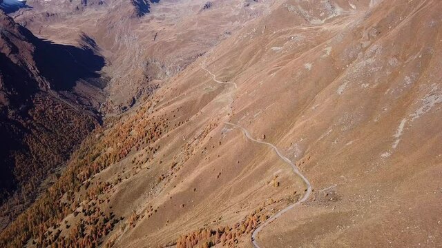 Road to the Gavia mountain pass in Italy. Amazing aerial view of the mountain bends creating beautiful shapes. Fall time. Warm colors. Nobody on the road