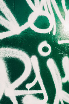 White spray painted graffiti on green metal container