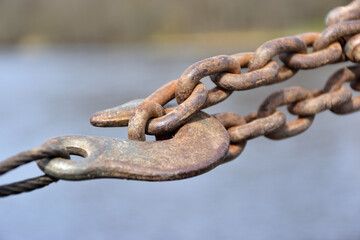 Rusty chain with a hook stretched on a pier