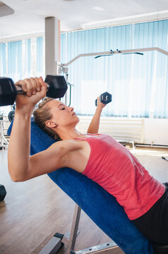 Woman at the gym doing chest workout with dumbbells