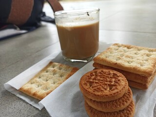 A cup of milk chocolate on a white background with crispy cake in a city park.