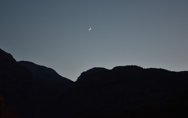 Rising moon against the background of the dark silhouette of the mountains