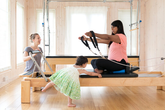Pregnant mother trying to undertake Pilates exercise with the help of her two year old daughter