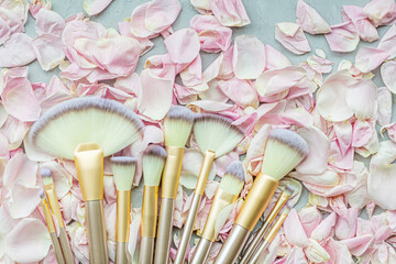 Cosmetic Makeup brushes on pink rose petals. Flat lay, top view, copy space. Makeup accessories, mockup, template