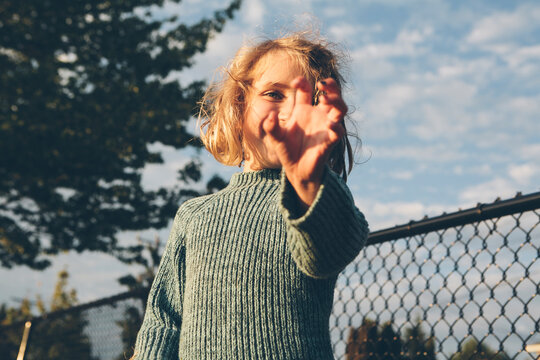 Happy six year old girl reaching towards camera with hand