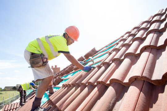 Professional Roofers installing new roof on building.