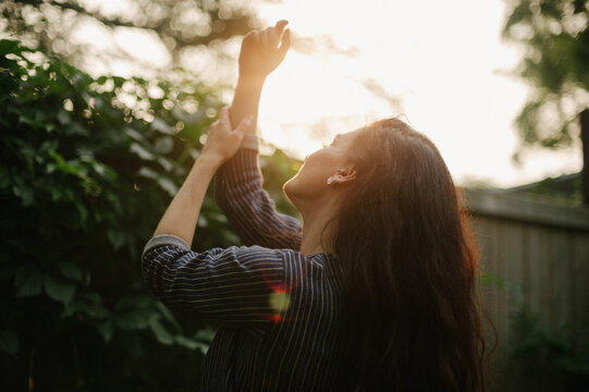 Pretty dark haired woman in alleyway with sunburst light at sunset