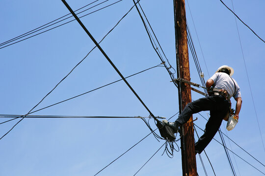 Man hanging on a telephone pole working