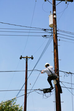 Man hanging on a telephone pole working