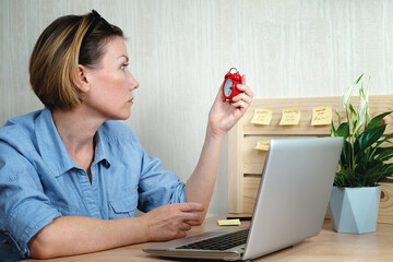 Woman sitting near laptop and looking at watch