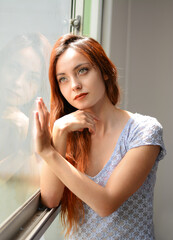 Mujer pensativa mirando a travez de la ventana