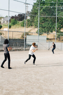 three friends pretend to hit each other with baseballs