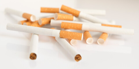 Cigarettes with a yellow filter lie on a white surface